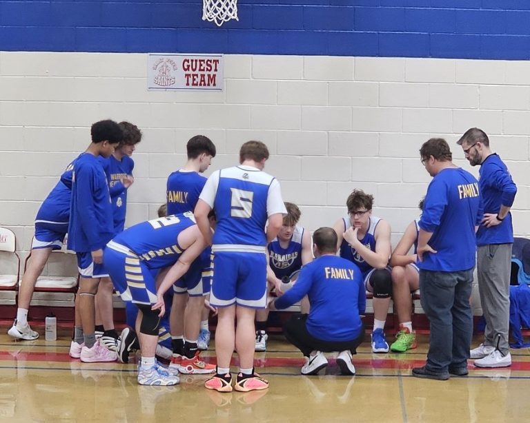 Decatur Christian Warriors basketball players and coaches huddle at the bench during a game