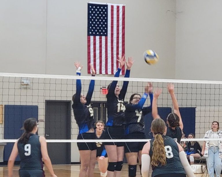 Decatur Christian volleyball players jump to block at the net